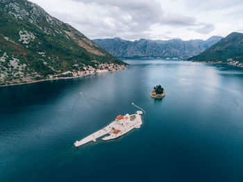 High angle view of sea by mountains against sky