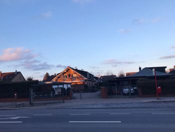 Road by buildings against sky at dusk