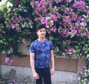 Portrait of young woman standing against purple flowering plants