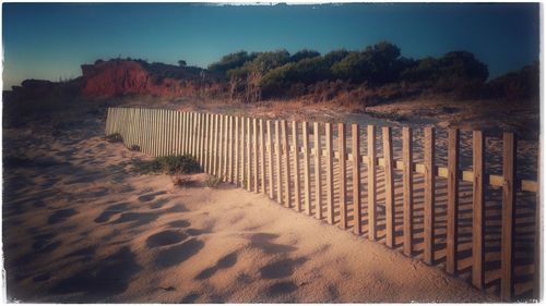 Fence on beach against sky