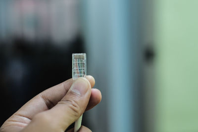 Cropped hand of person holding cable against defocused background