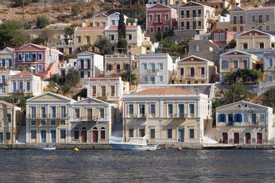 Houses by river against buildings in city