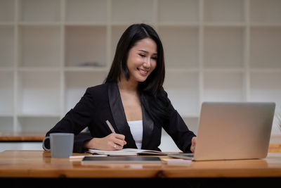 Young woman using phone while sitting on table