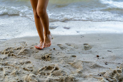 Low section of woman walking on beach