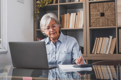 Mid adult man using mobile phone while sitting on table