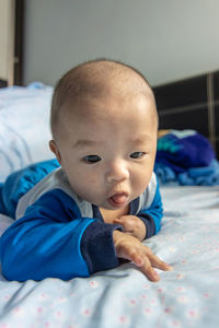 Portrait of cute baby lying on bed at home