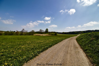 Road amidst field against sky