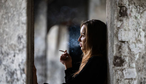 Side view of woman looking through window