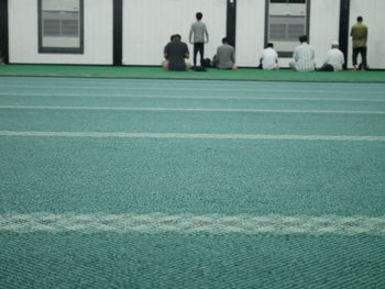 People playing soccer ball on field against building