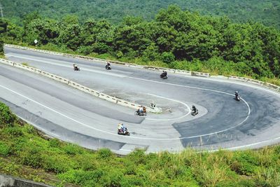 High angle view of people riding motorcycle on mountain road during sunny day