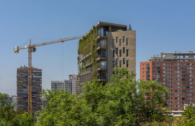 Green skyscraper building with plants growing on the facade, santiago, chile