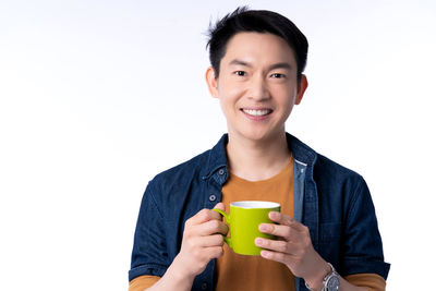 Portrait of smiling man holding ice cream against white background