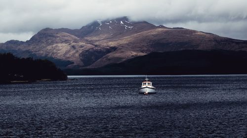 Sailboat sailing on sea against mountains