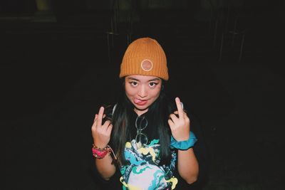 Portrait of woman showing middle fingers at night
