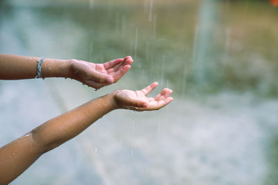 Raindrops splashing on cropped hands