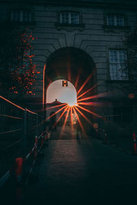 Illuminated footpath amidst buildings in city at sunset