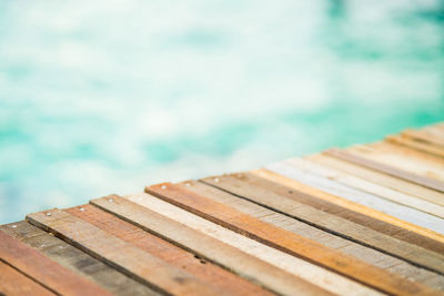 Close up top of wooden deck at sunrise beach. turqoise green sea in the background.