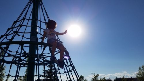 Low angle view of girl standing on rope against clear sky