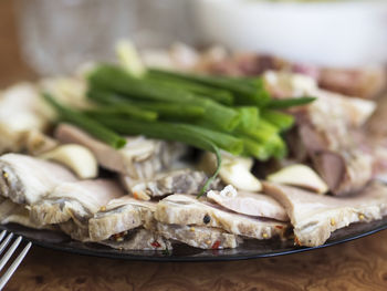 Sliced boiled pork and green onion on a plate on a table