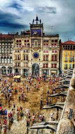 People walking in city against cloudy sky