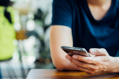 Midsection of man using mobile phone on table