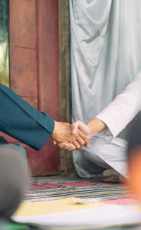 Midsection of man holding hands on table