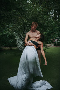 Young couple sitting on grass against trees