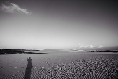 Man standing on sand at beach against sky