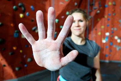 Young woman gesturing stop sign against climbing wall