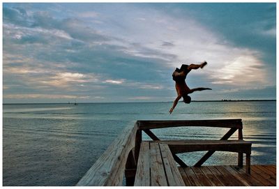 Silhouette of woman jumping on beach