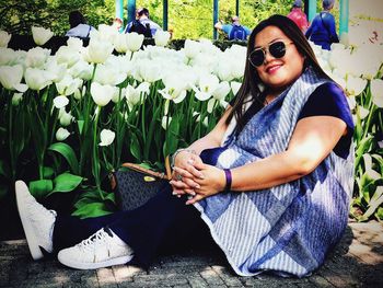 Portrait of smiling young woman sitting by potted plant