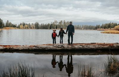 Rear view of men standing by lake against sky