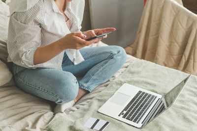 Woman at home on bed makes purchases on the internet. the joy of the black friday sale.