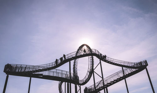 Low angle view of silhouette people on tiger and turtle magic mountain against sky