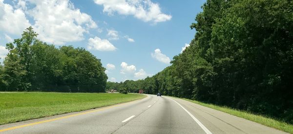 Road amidst trees against sky