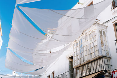 Low angle view of curtain by building against blue sky