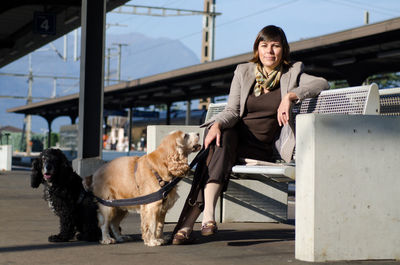 Full length of woman with dogs sitting on bench