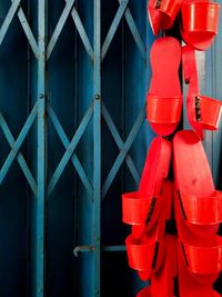 Close-up of red metal fence against blue wall