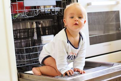 Portrait of cute boy on dishwasher