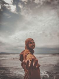 Woman standing at beach against sky