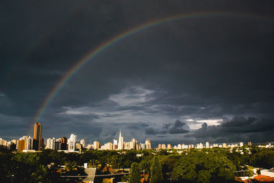 Rainbow over buildings in city against sky