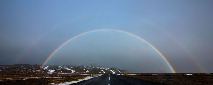 Scenic view of rainbow over road against sky