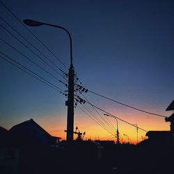Low angle view of silhouette electricity pylon against sky