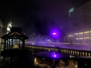 Illuminated bridge over river against sky at night