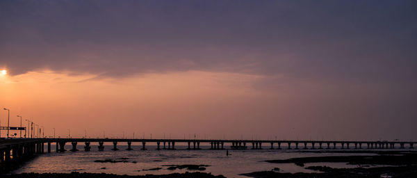 Bridge over sea against sky during sunset