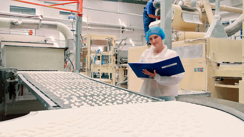 Low angle view of young woman standing in factory