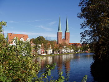 Canal amidst trees and buildings against blue sky