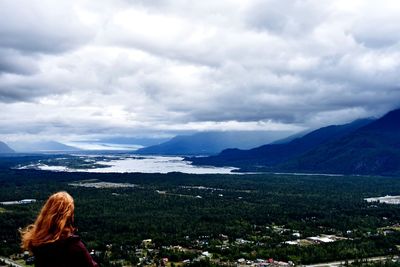 Rear view of woman looking at mountains against sky