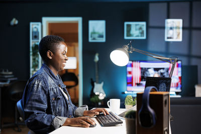 Side view of man using mobile phone while sitting at home