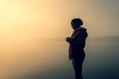 Side view of man standing against sky during sunset